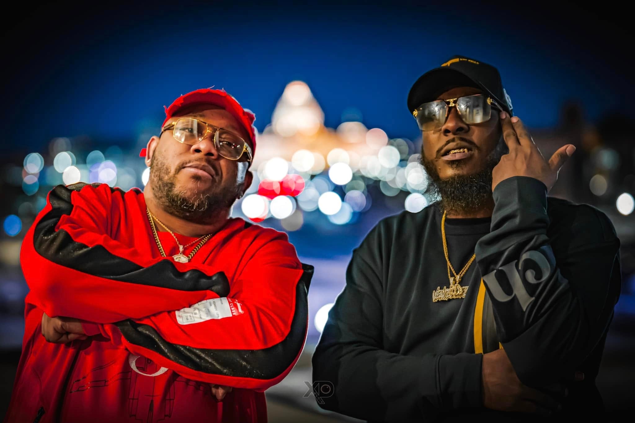Two artists posing against city night skyline