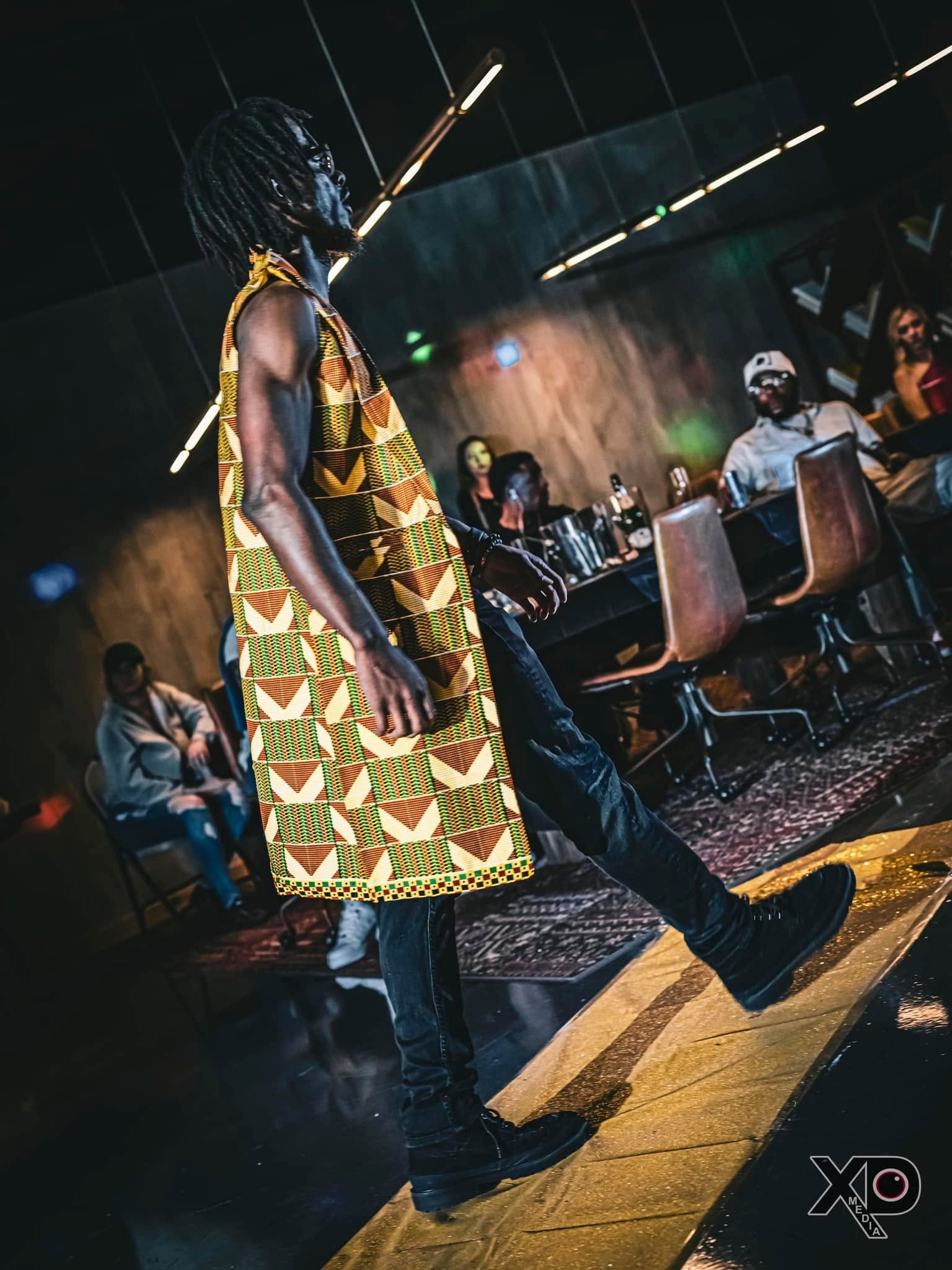 Man in kente cloth walking runway at fashion show