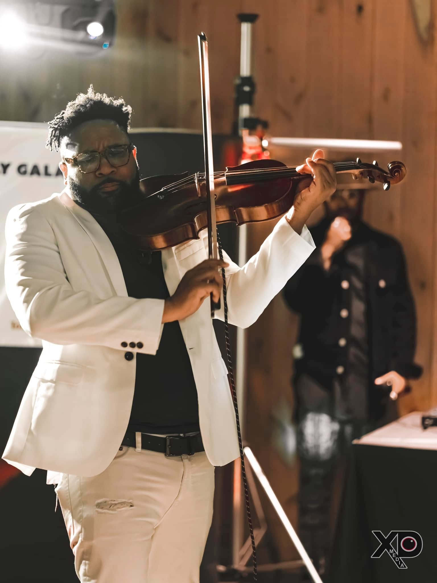 Violinist performing in white suit at gala event