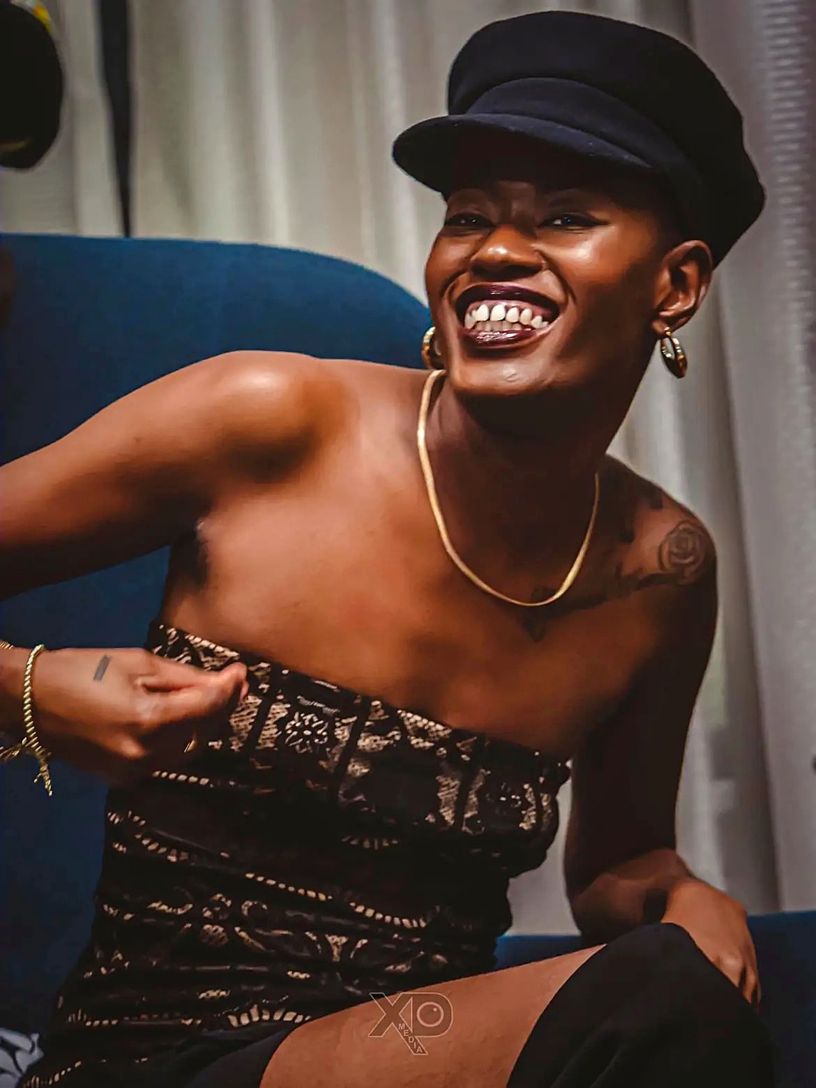Artist laughing in black hat and gold jewelry — portrait session