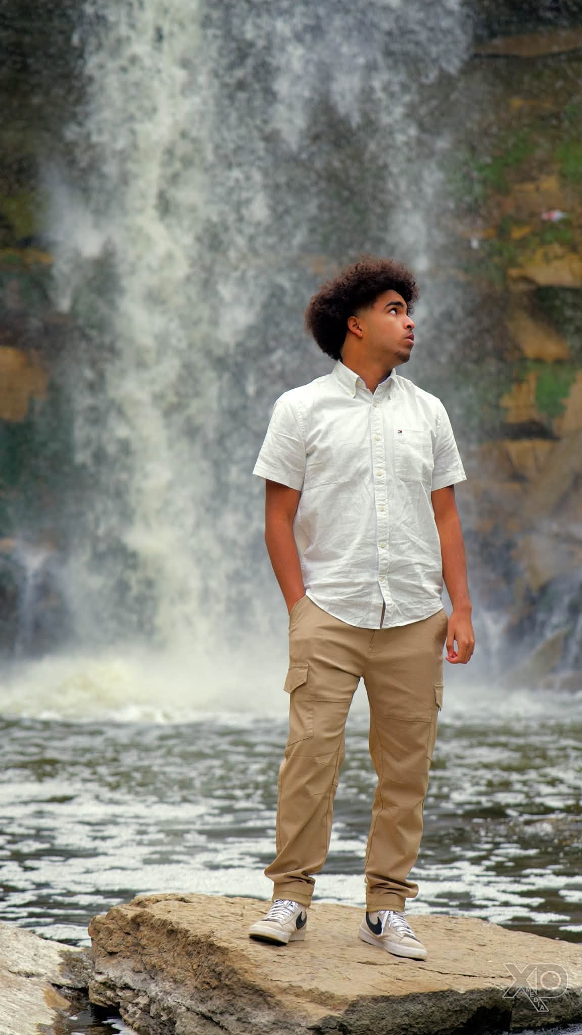 Young man standing at waterfall