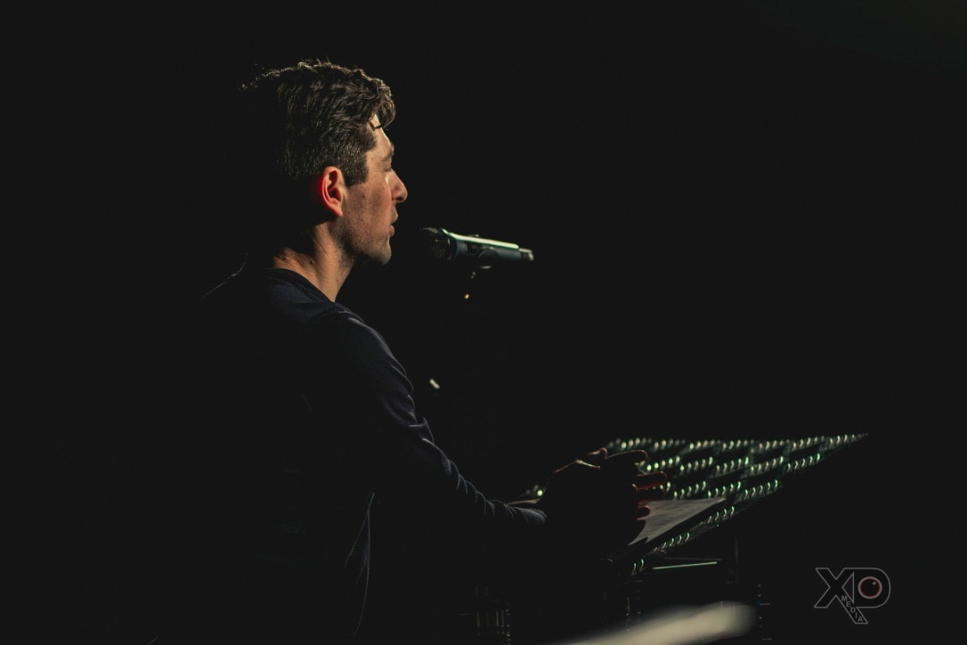 Moody, low-light profile portrait of Jacob Frey at a microphone stand